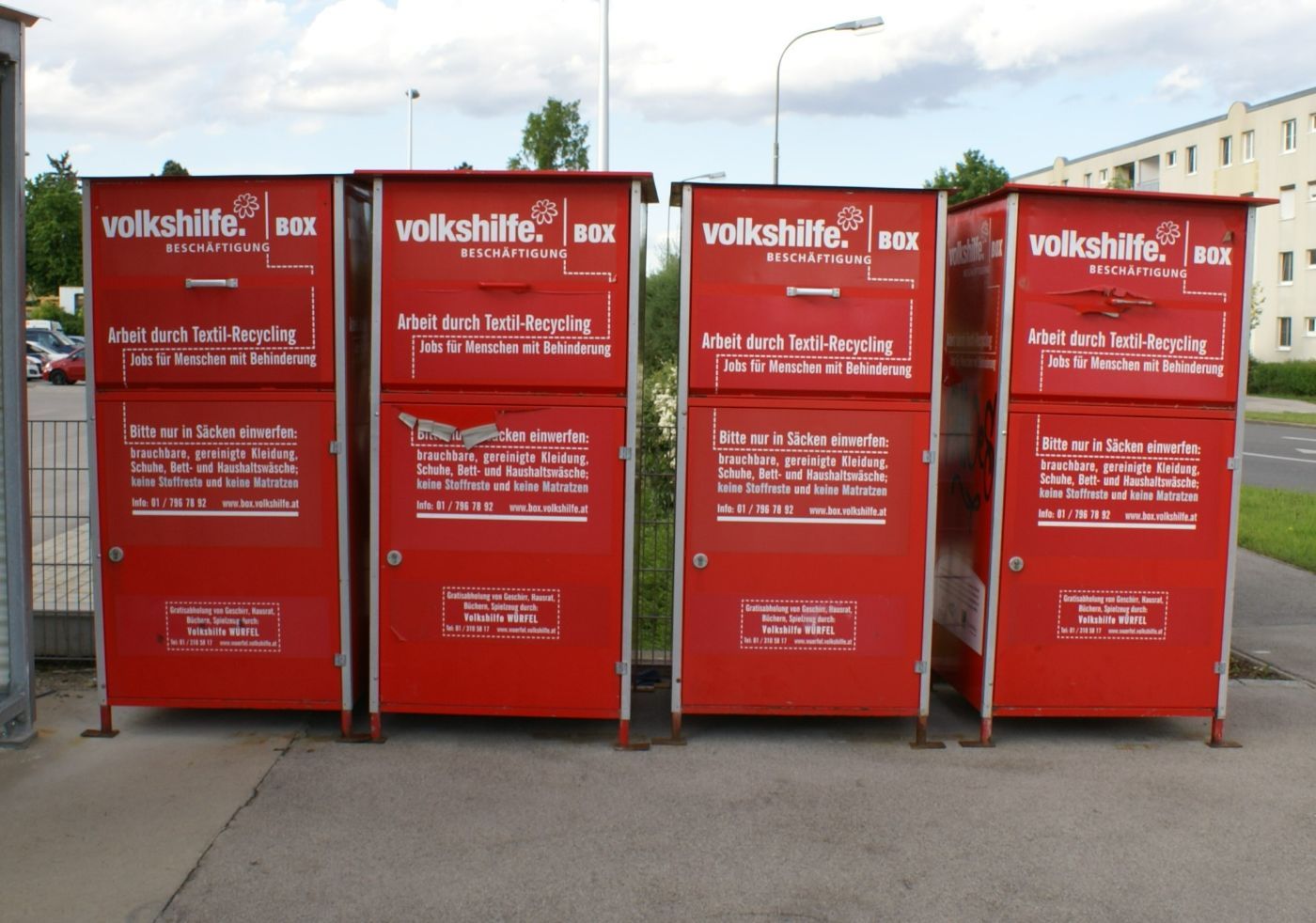 Vier rote Altkleidercontainer von der Volkshilfe