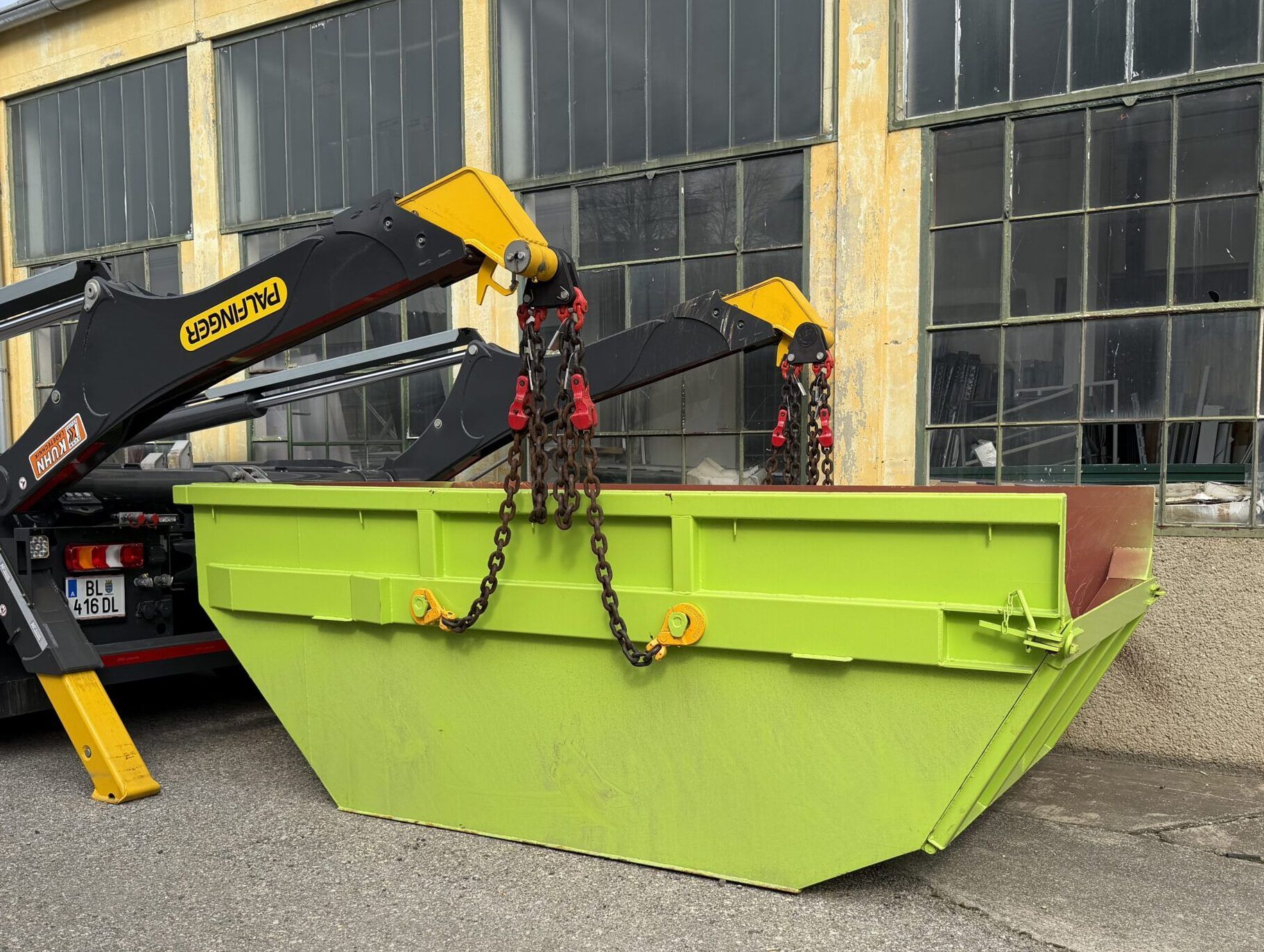 Hellgr&uuml;ne 8m<sup>3</sup> Absetzmulde, die gerade von einem LKW abgestellt wird