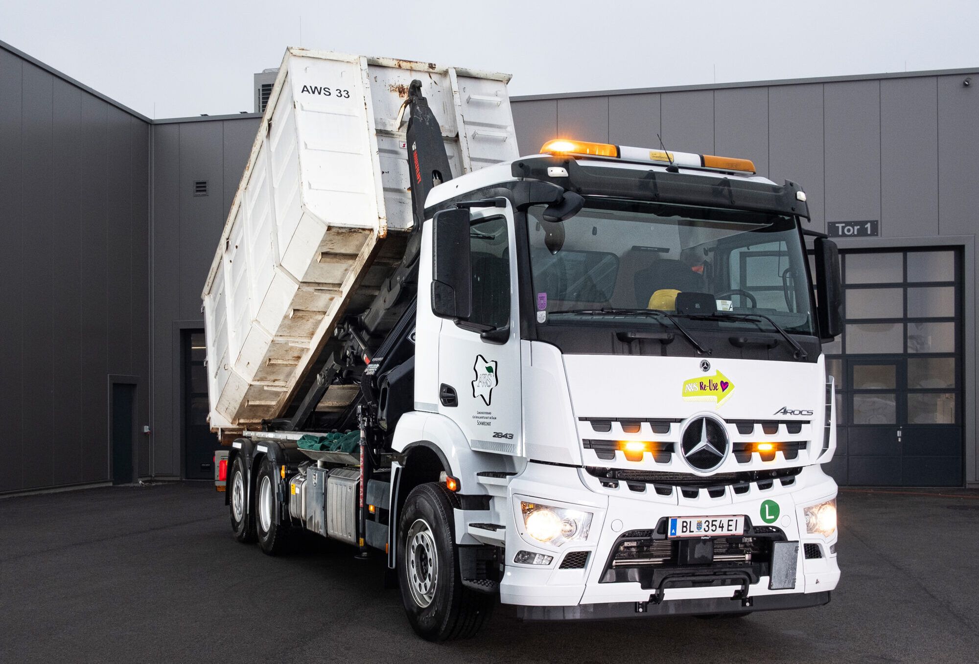 ein LKW steht vor einer Lagerhalle, der LKW ist dabei einen Container abzuladen